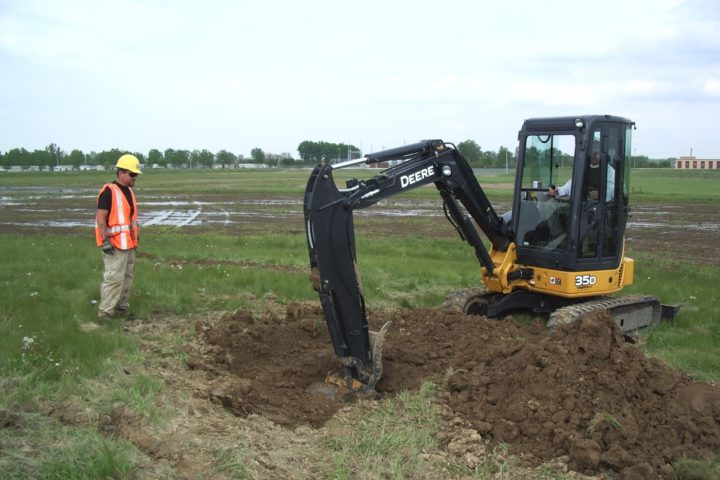 worker standing next to a backhoe