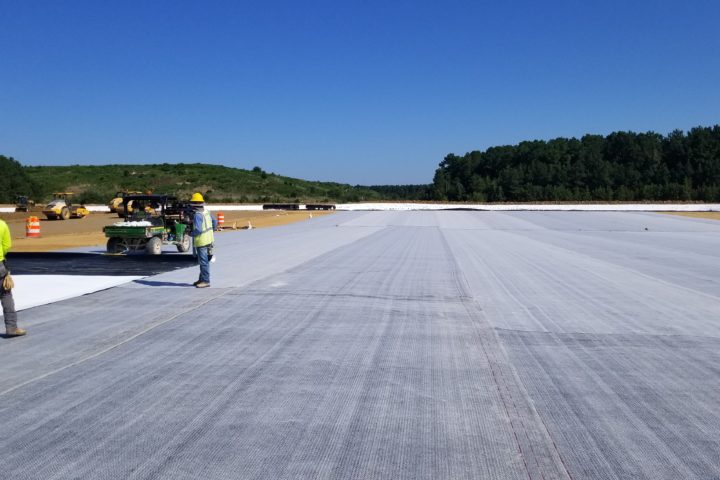 Construction workers install a liner along the floor of a landfill cell