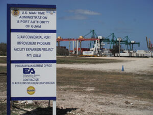 Sign in the forground with port cranes in the background.
