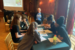 An EA employee standing at a table with a group of kids teaching them on a scientific subject at the SAME Baltimore Post Easy as Pi event.