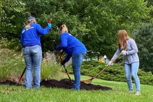 Three EA employees spreading mulch into flower beds at the Maryland zoo