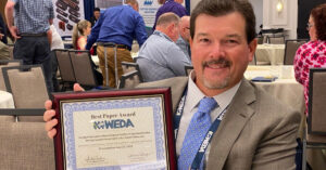 At the WEDA conference, Jamie Beaver holds the just-bestowed Best Paper Award plaque for the design optimization for a dredged material confined disposal facility.