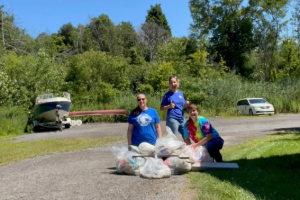 EA team members standing behind multiple filled trash bags after stream cleanup.