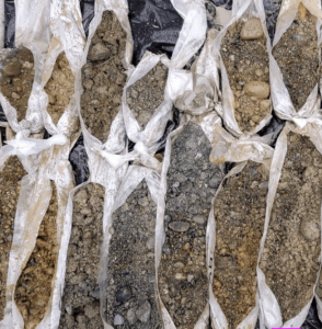 Two rows of bags of soil with different colors, consistencies, and grain sizes