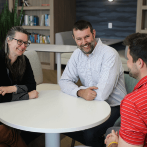 Three smiling EA employees at a table having a meeting