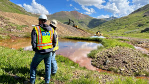 Two EA employees in personal protective equipment on a construction site in the mountains