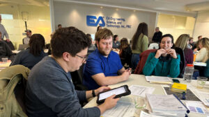 Three EA employees at a table during a training summit exploring use of a new application on a tablet