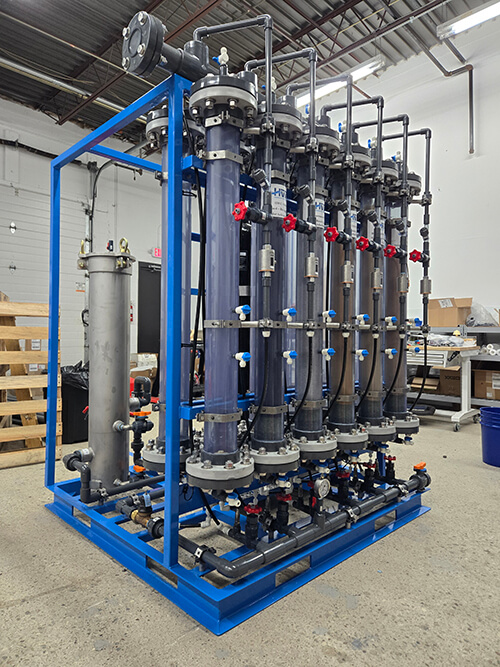 - Pilot system featuring 12 vertical cylinders and complex valves, piping, pumps, and metering prior to installation at a water treatment plant. 