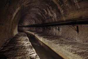 Underground vaulted urban sewer tunnel with dirty sewage.