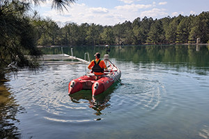 EA scientist in an inflatable raft collecting data in the water-filled pit of the Barite Hills mine.
