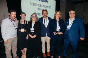 Peggy Derrick at the WEDA banquet holding the lifetime achievement award with other representatives from EA.